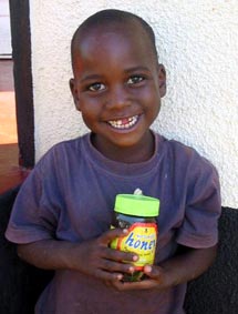 Young boy smiling with holing jar of honey.